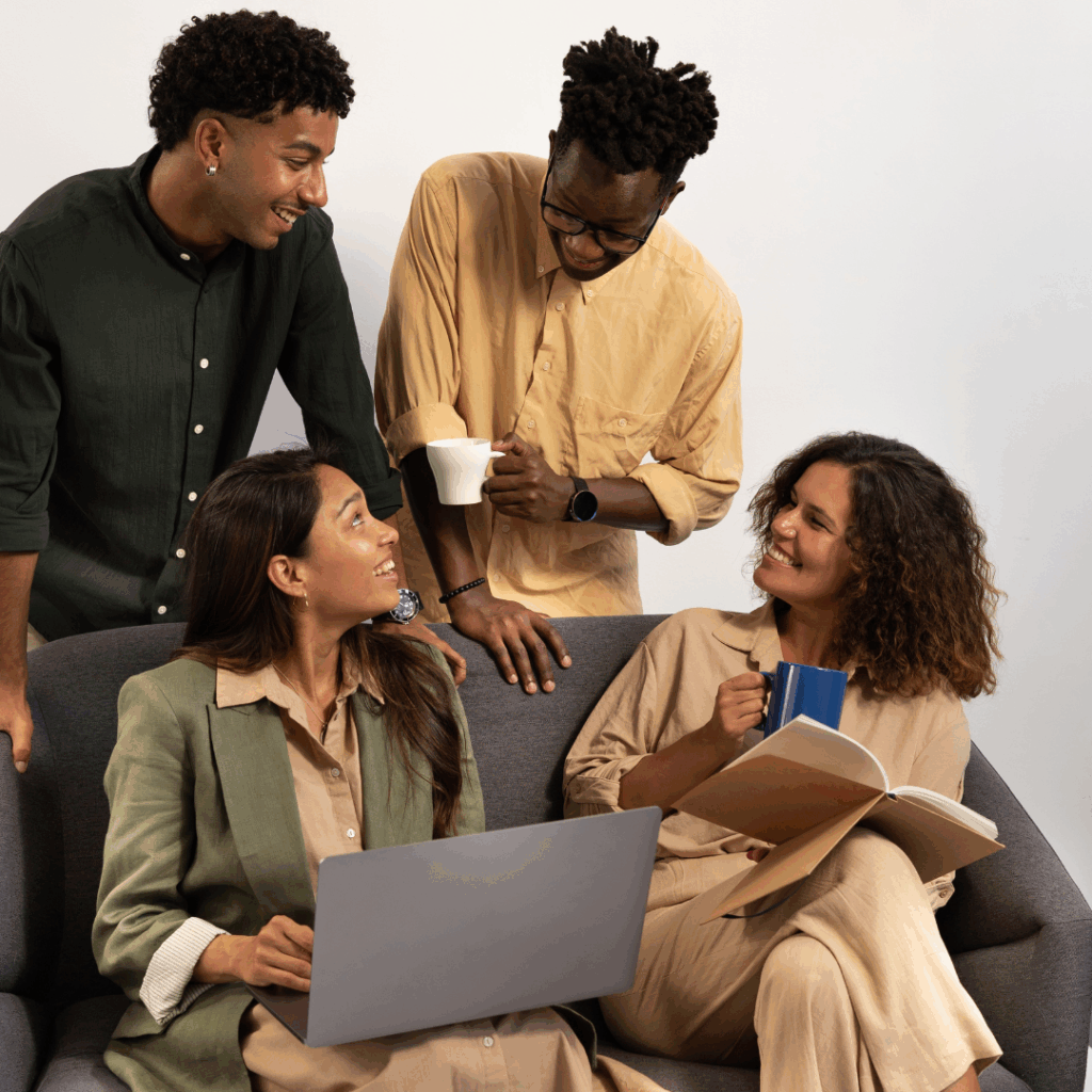 Friendly business team having an informal discussion on a sofa with coffee and a laptop